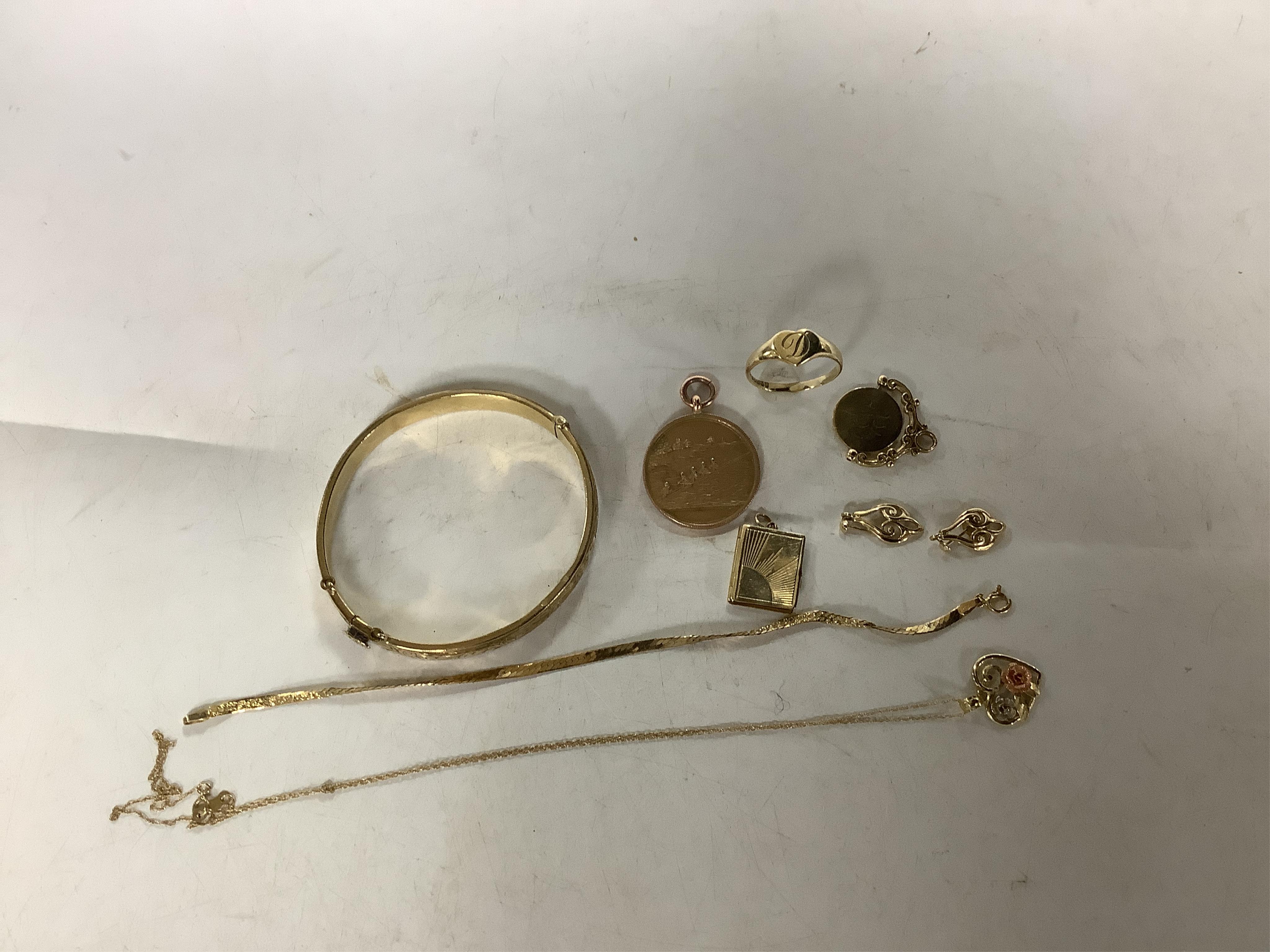 A collection of gold jewels and a filled gold bangle, comprising: a medal for the West of England Amateur Rowing Association dated 1929, length 3.6cm; a spinning disc pendant reading 'I LOVE YOU'; a heart-shaped signet r
